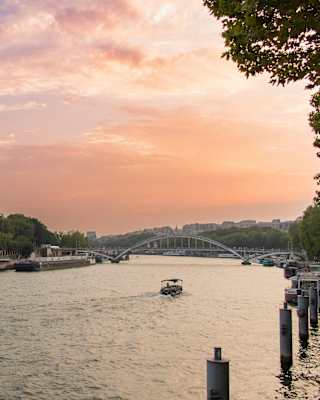 View from the Right Bank over the river Seine to the Left Bank, where the iconic Eiffel Tower rises against a plum sunset sky.