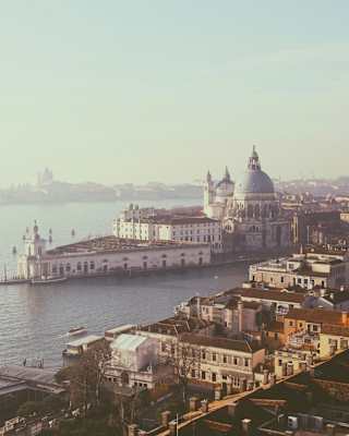 Aerial view above San Marco, looking over the Grand Canal and Punta della Dogana to Giudecca, bathed in a haze of morning sun.