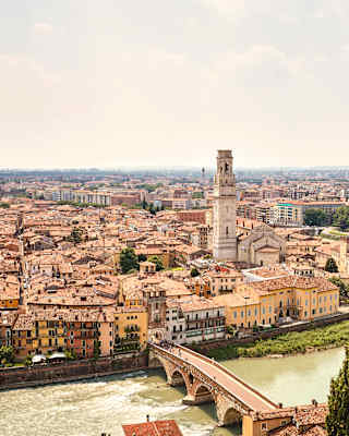 View of Ponte Pietra bridge crossing the Adige River to Verona's centre where the Torre dei Lamberti rises above tiled rooftops.