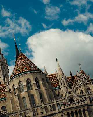 Tilted low-angle image of the patterned, fairy tale roofs and spires of the church of our Lady of Buda Castle Matthias Church.