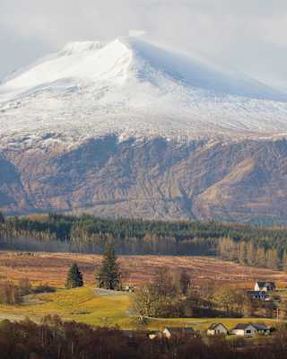 The mountain of Aonach Mor, linked by a mountain pass to Aonach Beag, rises from the glen, gathering snow as it ascends.