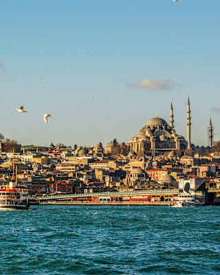 View across the choppy Bosphorus Strait, where a ferry chugs towards Istanbul's rooftops, minarets and Suleymaniye Mosque.