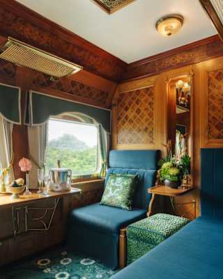 A velvet peacock-blue window seat soaks in views and luxury of the State Cabin, as champagne chills in a bucket on the table.