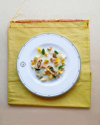 A dish of Black-bone Chicken Consommé, created by Chef Andre Chiang, with cauliflower and cashews, on a lime-yellow napkin.