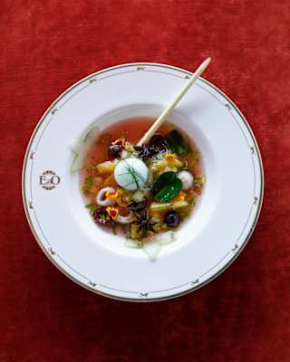 Chef Andre Chian's “nine peppers jus” herby sixteen-hour-braised beef cheek, served in a white bowl on a red tablecloth.