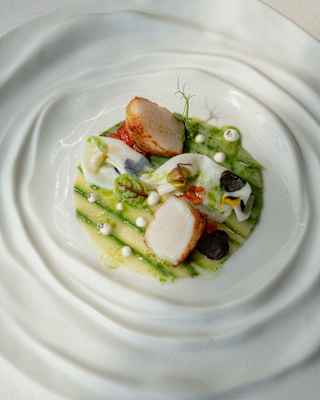 Seared scallops served on asparagus strips with garnish create a garden in the centre of one of Otto Geleng's unique plates.