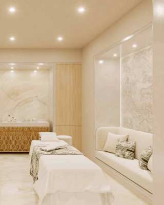View of two treatment tables with Toile de Juoy throws in a bright, clean Dior spa room with spotlights, banquette and sink area.