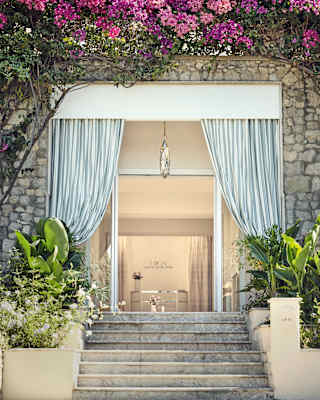 Stone steps, flanked by plant beds, ascend to Dior Spa's glass entrance, topped by pink bougainvillaea and framed by tied drapes.