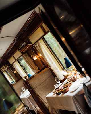 Tilted image of a restaurant car with a dining table laden with dishes of food, illuminated by window light.