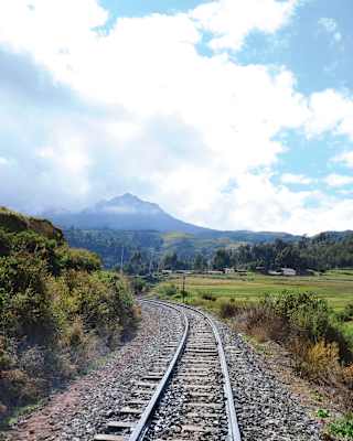 Train tracks winding along a valley towards a Peruvian mountain top