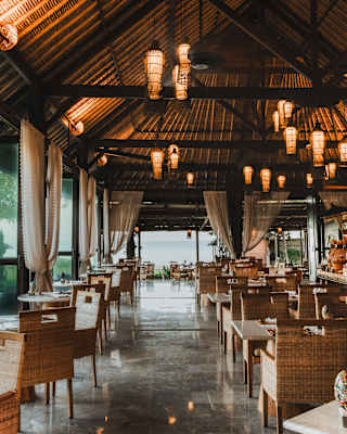 Clusters of lanterns glow above the tables and wicker chairs of Tunjung restaurant, with windows out to the sea and gardens.