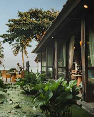 Bifold doors open to immediate views of the lily pond bordering Tunjung restaurant, with the terrace and ocean seen beyond.