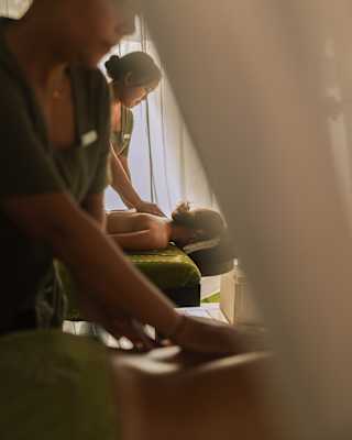 A staff member at the Beach Spa massages the back of guest, seen over the arms of other masseuses in soft-focus foreground.