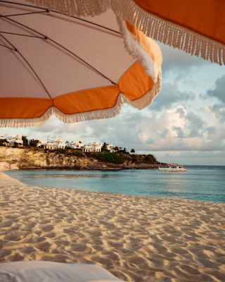 White villas perch on the cliffs south of Baie Longue, viewed across the rippled sand of Long Beach from beneath parasols.
