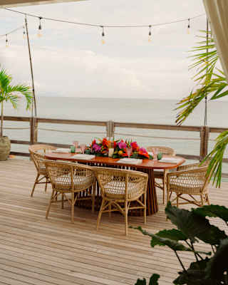 A dining table with six cane chairs and a large exotic-flower centrepiece awaits guests on the sea-view deck at Laplaj.