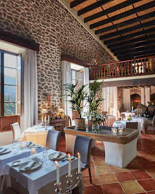 Interior of a formal restaurant with a terracotta-tiled floor and wooden balcony