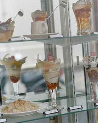 Glasses of cherry-topped sundaes and trifles on display in a shop window in Tokyo, photographed by Cecy Young.