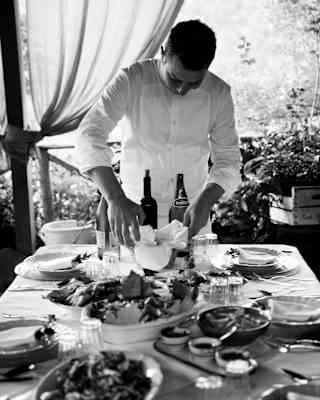 Caruso's Executive Chef Armando Aristarco puts the finishing touches to a table laden with food, shot in black and white.