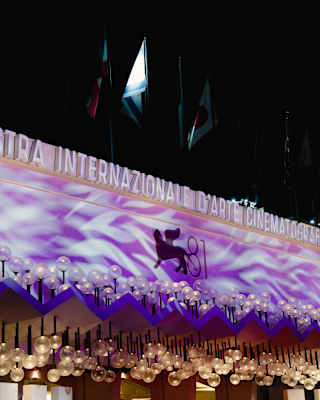 A purple cinema awning, glowing with white ripples and dripping with globe lights, advertises the eighty-first film festival.