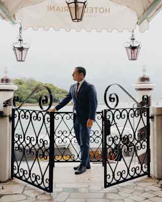 Andrea Zennaro, doorman at Hotel Cipriani, prepares to greet guests at the filigree gates under the hotel's entrance awning.