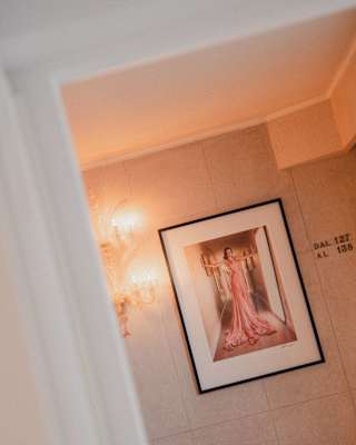 A framed print of Greg Williams' photograph of Ana de Armas in a Luis Vuitton pink dress adorns a corridor wall, at an angle.