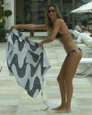 Brazilian model, Gisele Bündchen holds a waiter's apron like a matador as she plays around at the poolside in a black bikini.