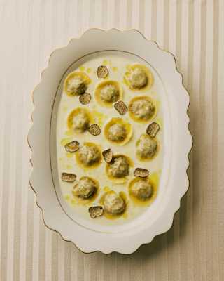 Looking down on a scallop-edged dish of wild boar tortellini served in am unctuous creamy, buttery sauce with truffle shavings.