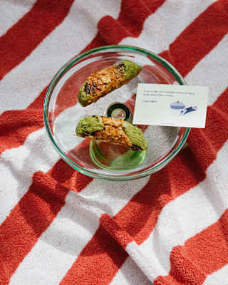A card balanced on a glass bowl with two pistachio cornetti says a trip isn’t complete without bringing home something sweet.