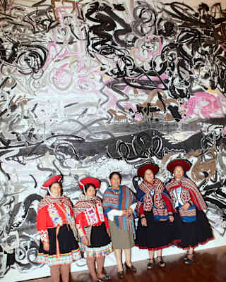 Five Peruvian women in bright woven shawls, four in montera hats, stand in front of large-scale ink artwork by Wu Jian'an.