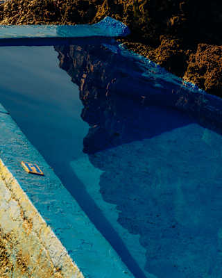 Reflections of rock float in the water of the blue-painted pool in a detail of the sea platform below Reid's Palace.