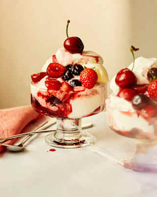Close-up of two glass bowls of Paciugo, made with layers of gelato, whipped cream, summer berries and Amarena cherries.