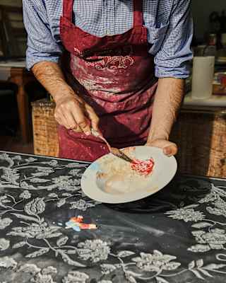 Bianco Bianchi, seen from the neck down in a red apron, prepares a Scagliola plaster paste to add inlay to an etched artwork.