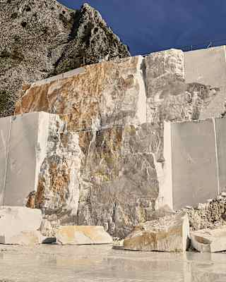View of creamy marble in raw form with smooth patches where blocks have been cut away, pictured in the Carrara mountains.