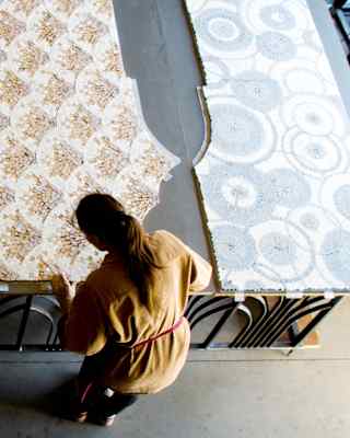 Seen from above, a craftswoman creates mosaic panels for the suites, with peacock, peaks, scallop and circle patterns.
