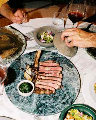 Linz cowboy ribeye grilled over zapote wood and served on a grey marble plate takes centre stage at a dining table at Woodend.