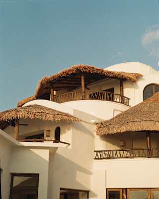 Low-angle view of Maroma's suites, moulded into a white structure with natural curves, wood railings and thatched balconies.