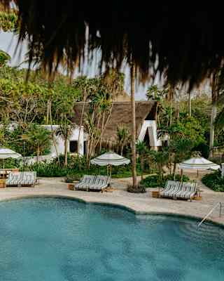 A shell stencilled on the bottom of the pool shows through its turquoise waters, overlooked by three pairs of loungers.