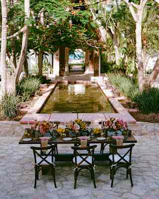 A laid table filled with flowers is ready for a celebration in Ranas Courtyard with views over the fountain and out to sea.
