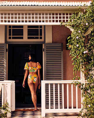 Woman in a two-piece floral print swimsuit walking towards her room