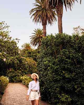 Smiling woman walking surrounded by flowers and leaves