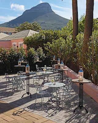 The pretty Green Park Room terrace with filigree tables and chairs, lantern stands and amazing views of Lion’s Head mountain.