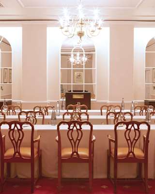 Three long tables span the intimate Orchid Room space, with arched wall mirrors, plush red carpet and ornately-carved chairs.