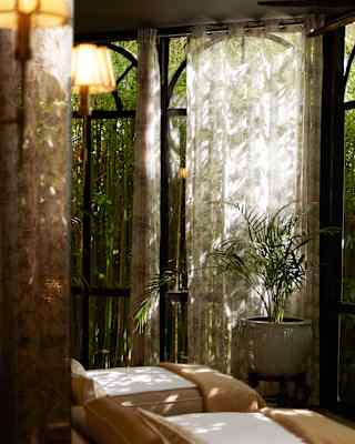 View of three chaise-longue chairs bathing in dappled light through drapes in the cool, restful air of the Librisa Spa.