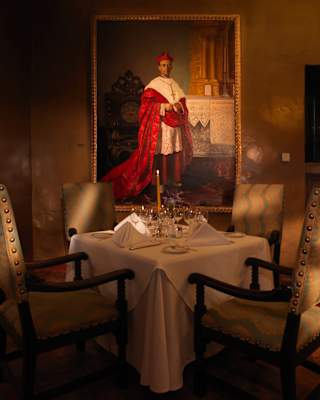 Table for four in a low-lit restaurant with a large portrait of a cardinal behind