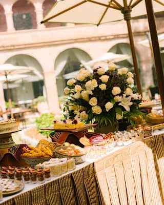 Tilted image of a large table with a white rose centrepiece and beautiful Sunday brunch offering of sweet and savoury dishes.