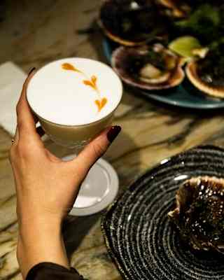 Close up shot of a guest's hand holding a cocktail at the Belo Bar