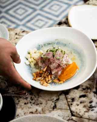 A waiter serves a white dish of fine cuisine at the Restaurant Tragaluz in Hotel Miraflores Park