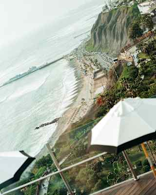 Angled image of the Lima coastline, where cliffs meet a busy road skirting the beach, taken from Observatory restaurant.