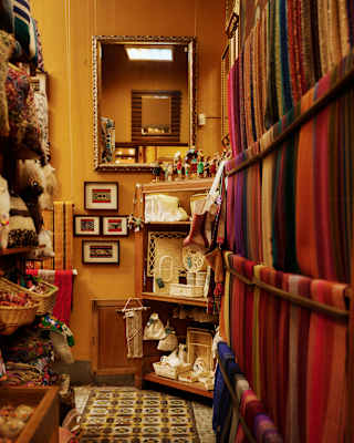 An aisle in a fabric shop featuring shelves of colourful textile rolls and framed wall art.