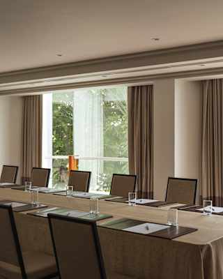 Snapshot of the Directorio room with a central table, flanked by chairs and place settings with paper and water glasses.
